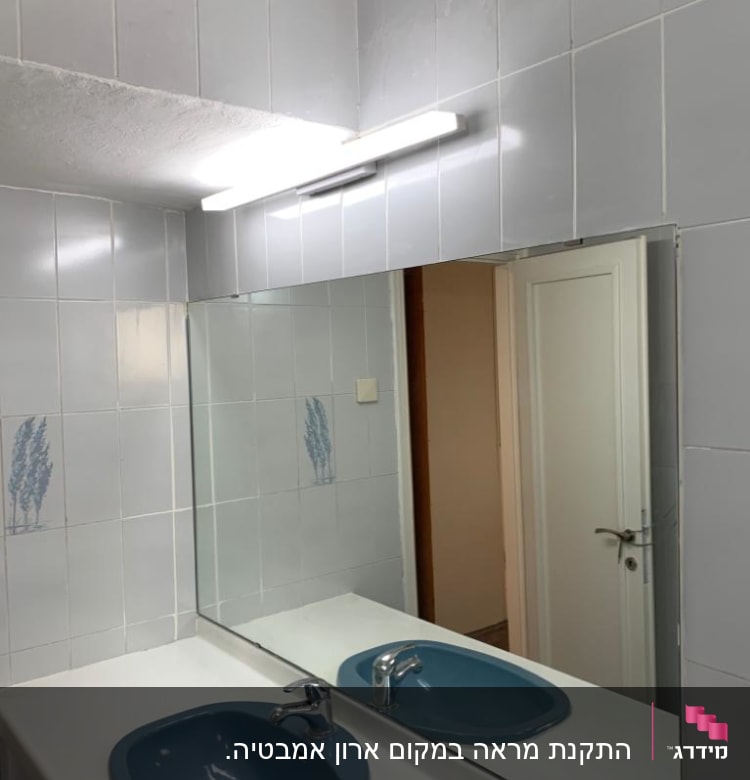 מראה גדולה מעל כיור בחדר אמבטיה